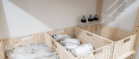 A storage area with wicker baskets containing toiletries and a white shelf with a light switch.