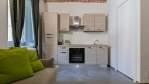 A modern kitchen with a built-in oven, a coffee machine, and a kettle on the countertop.