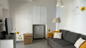 A modern living room with a grey sofa, a television, a radiator, and decorative sunflowers. - Nido Santa Chiara by Wonderful Italy (Torino)