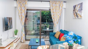 A modern living room with a sofa, coffee table, and a glass table with a vase of flowers. - Astoria Apartment  (Nairobi)