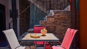 A small outdoor seating area with a table, chairs, and a potted plant.