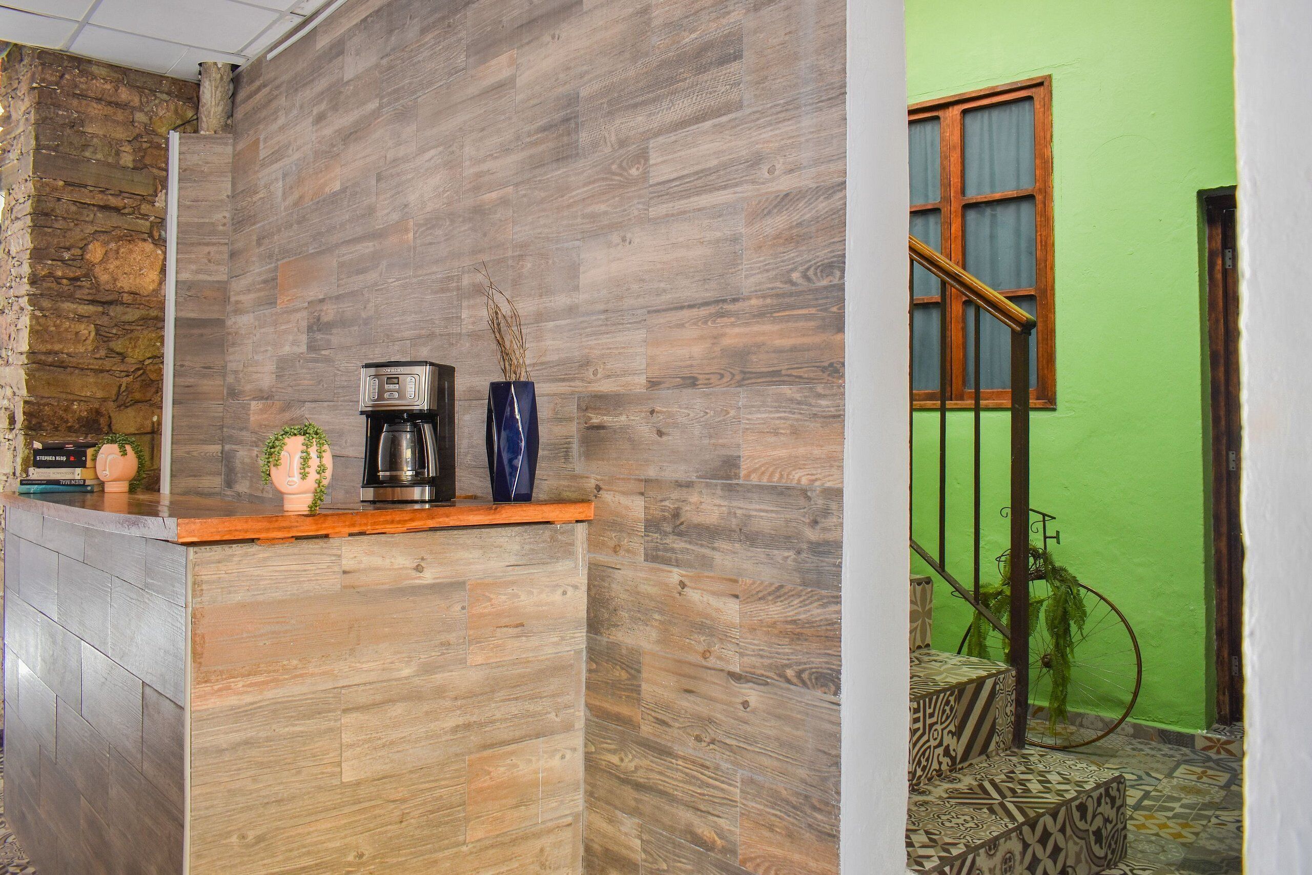 A reception area with a wooden counter, a coffee machine, and a vase with dried plants.
