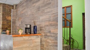 A reception area with a wooden counter, a coffee machine, and a vase with dried plants. - Doña Vicenta Casa Colonial (Guanajuato)
