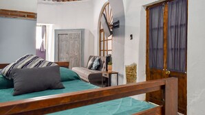 A bedroom with a bed, a wooden headboard, a nightstand, a dresser, a window with curtains, and a door.