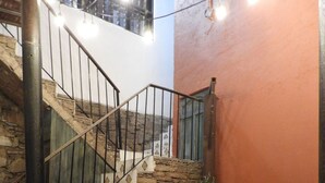A staircase with stone steps and metal railings, a table with chairs, and a potted plant.