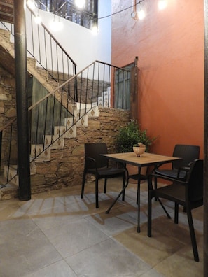 A staircase with stone steps and metal railings, a table with chairs, and a potted plant. - Doña Vicenta Casa Colonial (Guanajuato)