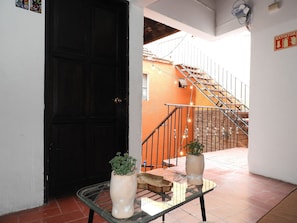 A hallway with a black door, a staircase with metal railings, and a potted plant on a glass table. - Doña Vicenta Casa Colonial (Guanajuato)