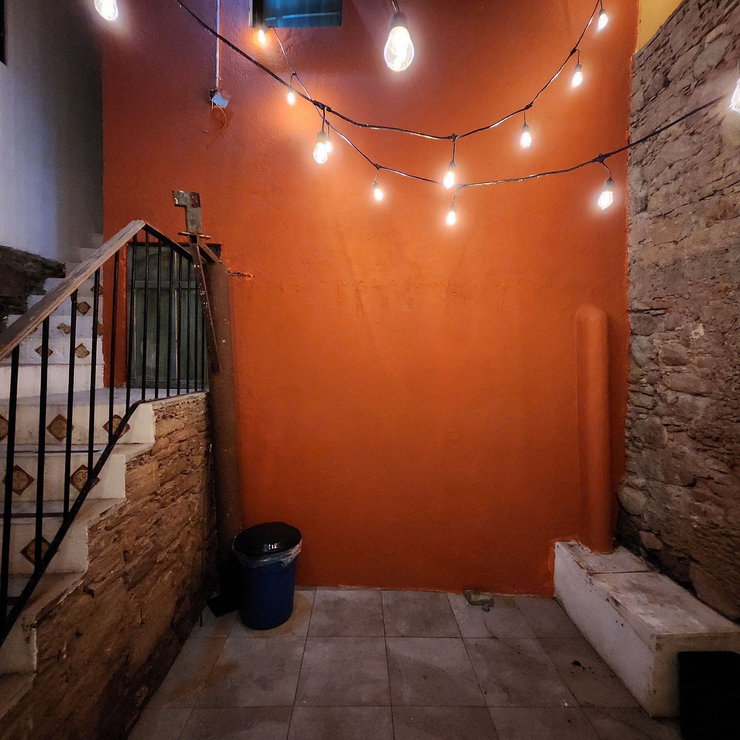A corner of a room with a brick wall, a metal staircase, and a string of lights.