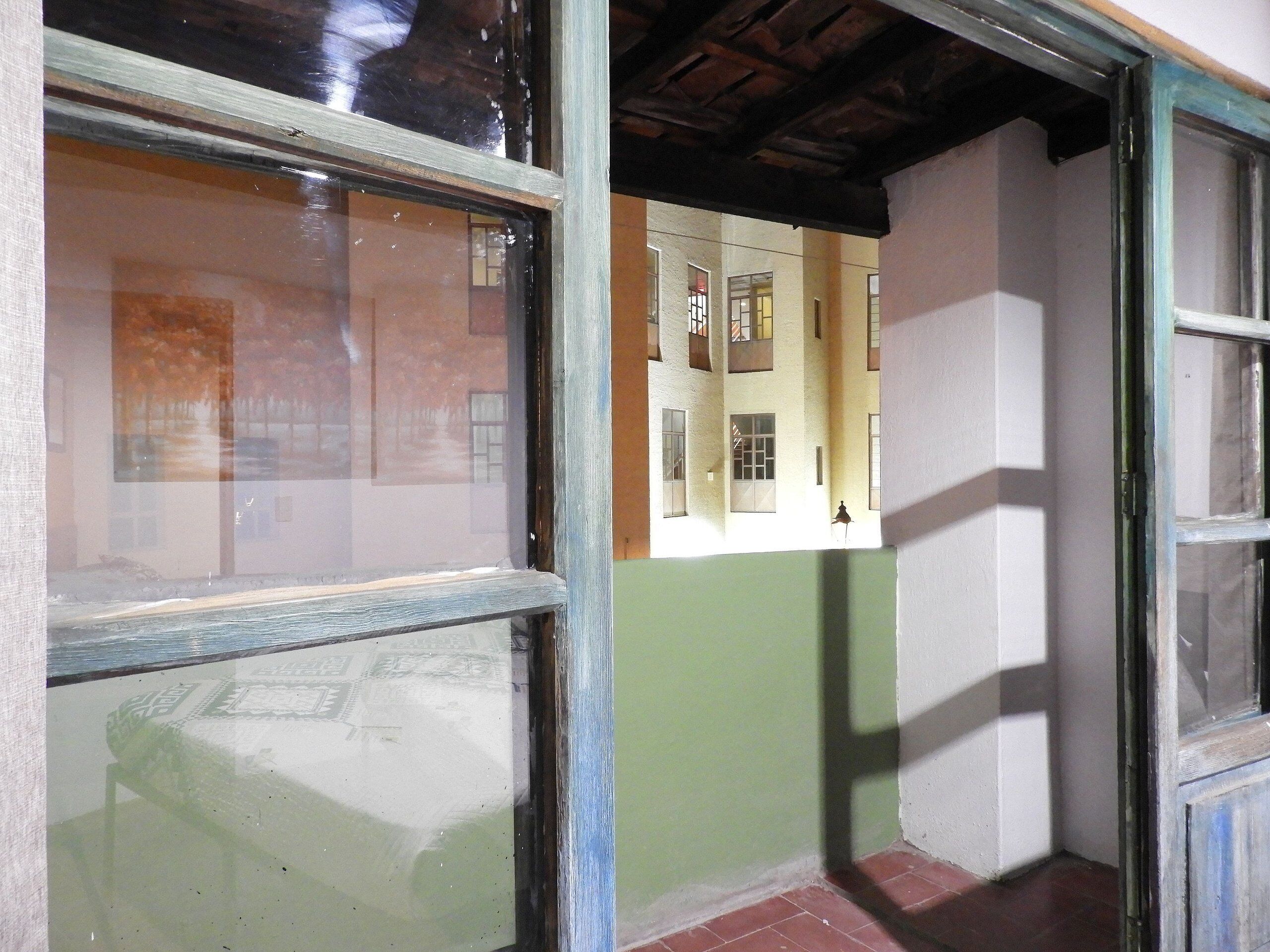 A narrow corridor with a window on the left and a door on the right.