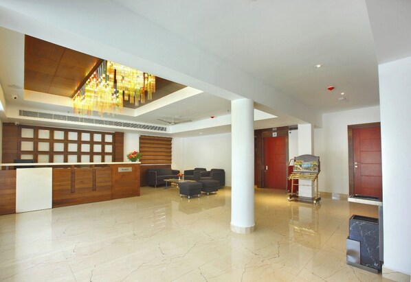 A spacious lobby with a reception desk, seating area, and a staircase leading to an upper level. - Embassery Residency (Kuruppampady)