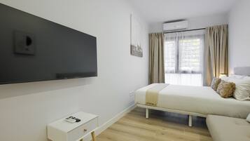 Un dormitorio moderno con cama, mesita de noche y televisor montado.