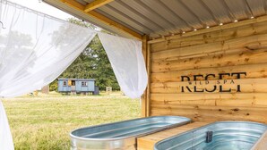 Un'area spa rustica in legno con due vasche in metallo e una parete in legno con il testo "RESET SPA WILD SULI".