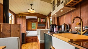 Un interior compacto con paneles de madera, una kitchenette, una cama y una zona de estar.