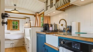 Cocina compacta con estufa integrada, un lavamanos y una ventana.