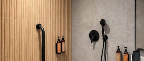 A modern bathroom with a wooden panel wall, a black showerhead, and a white sink.