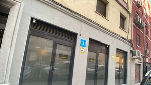 A building with large glass doors and windows, a sign indicating a business, and a parked car. - Dobo Madrid Río (Madrid)
