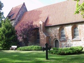 Une église avec un toit recouvert de tuiles rouges, des murs en pierre et une pelouse verdoyante avec un banc.