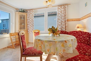 Una habitación con una mesa redonda, un sofá, un armario y una ventana con cortinas.