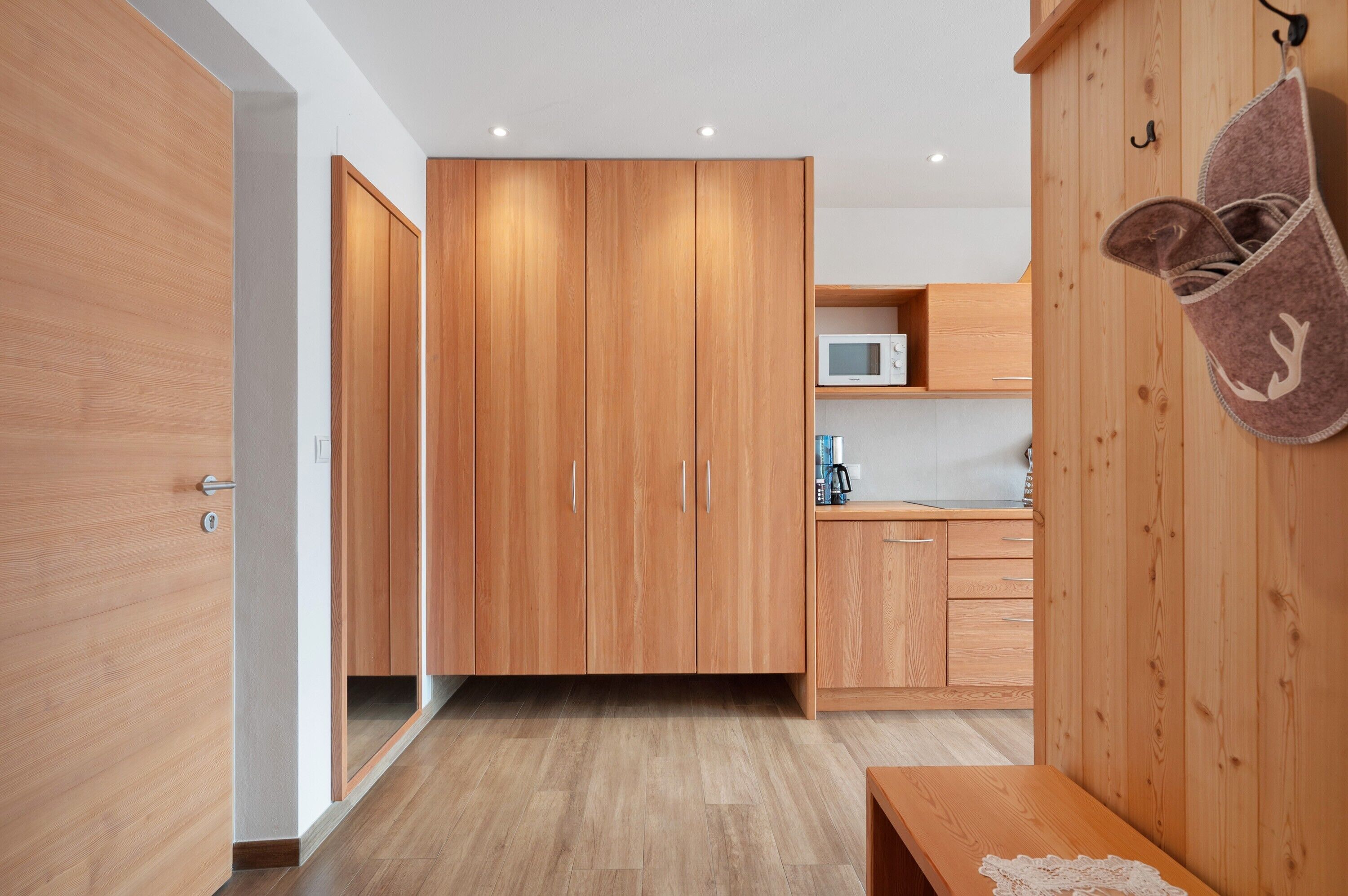 Una cocina moderna con armarios de madera, un microondas y un zapatero colgante.