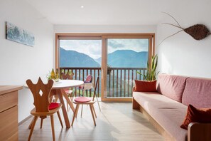A balcony with a mountain view, a dining area with wooden chairs and a table, and a sofa. - Apartment 'Kiefer' with Mountain View, Shared Terrace and Wi-Fi (Bolzano)
