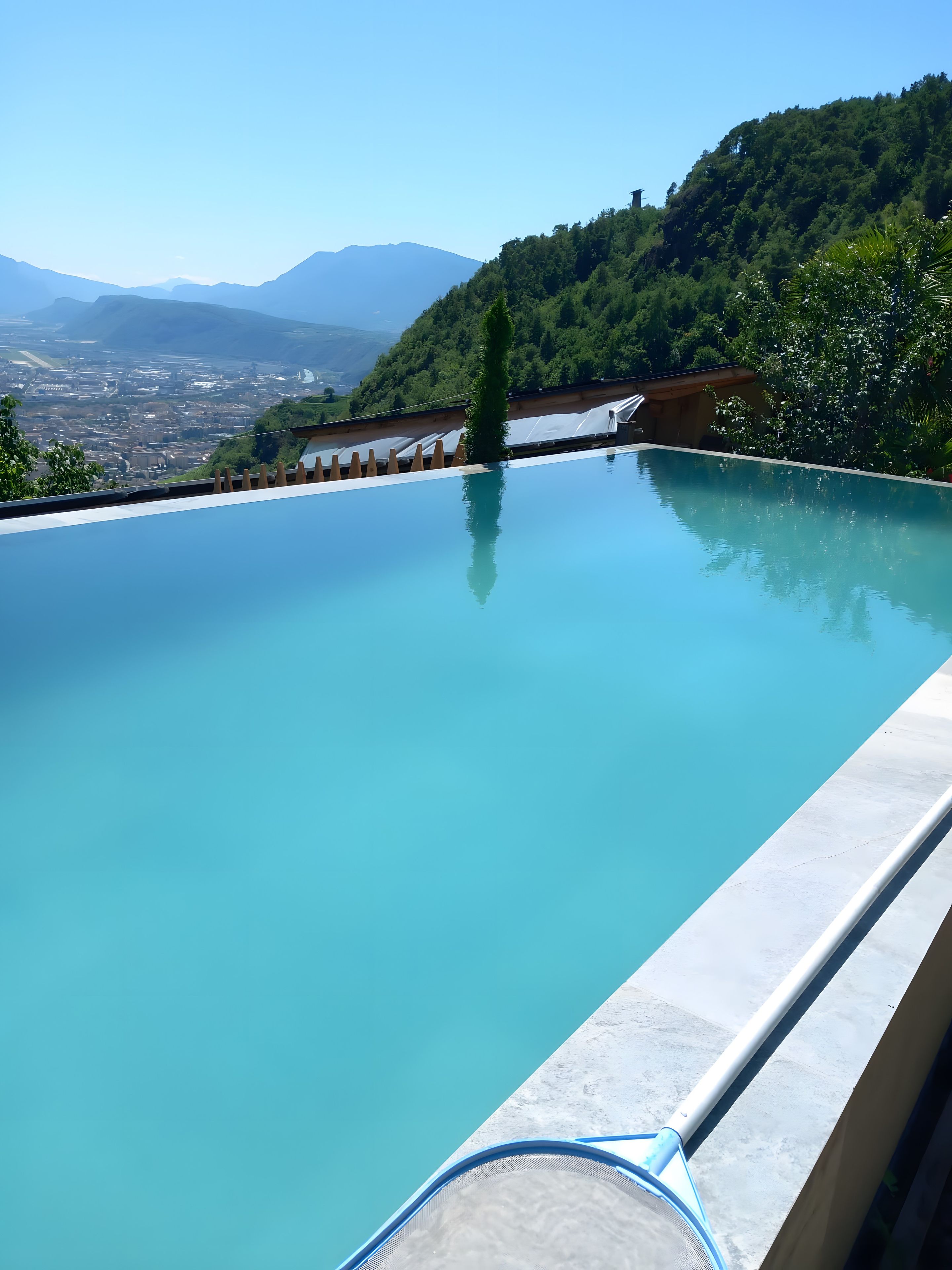 Ein klares, blaues Infinity-Pool mit Blick auf eine Stadtlandschaft und Berge im Hintergrund.