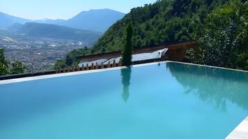 Ein klares, blaues Infinity-Pool mit Blick auf eine Stadtlandschaft und Berge im Hintergrund.