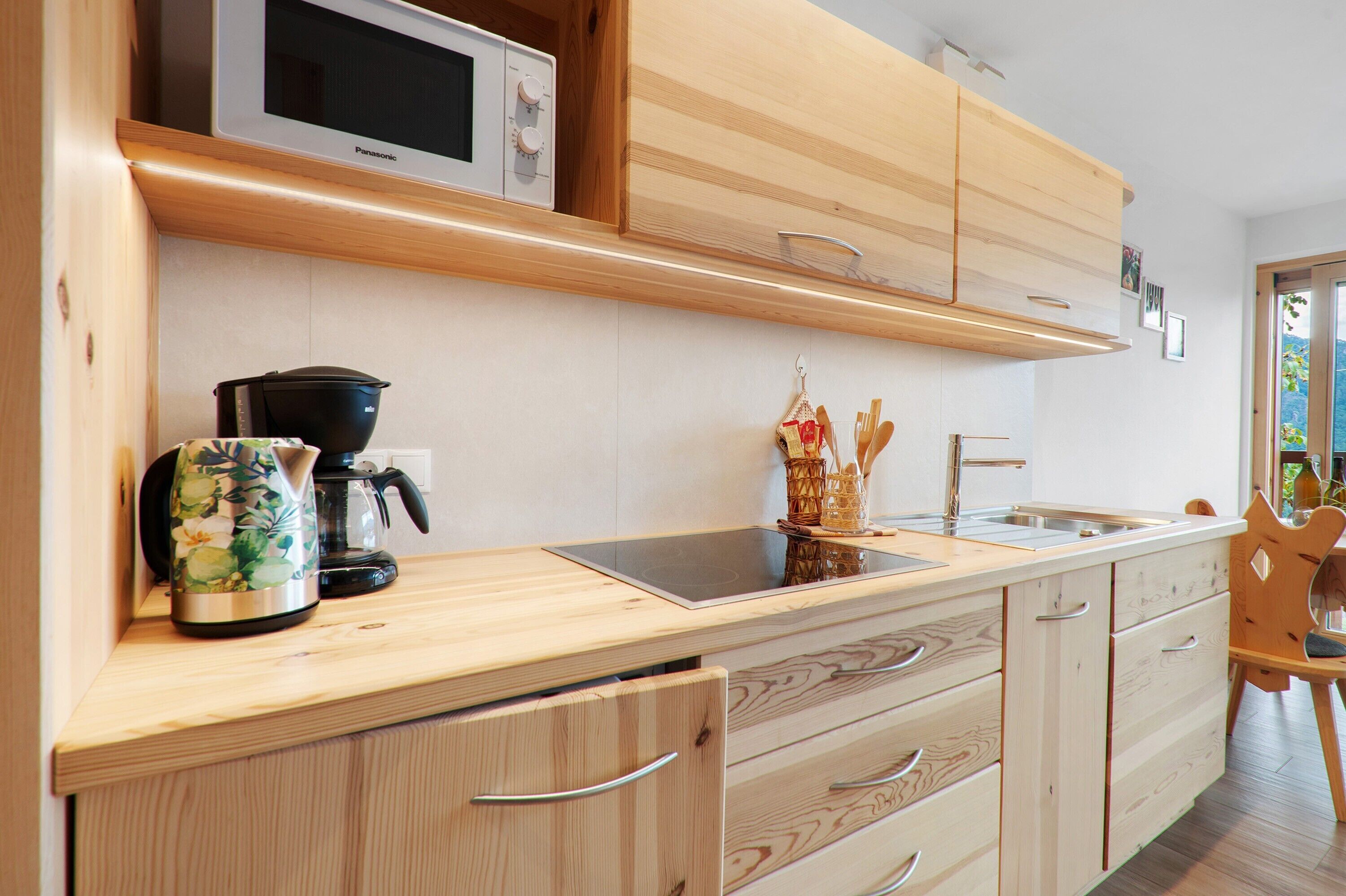 A modern kitchen with wooden cabinets, a microwave, a coffee maker, and a sink.