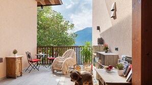 A balcony with a view of mountains, a wooden table, a rocking horse, and a chair. - Apartment 'Lärche' with Mountain View, Shared Terrace and Wi-Fi (Bolzano)
