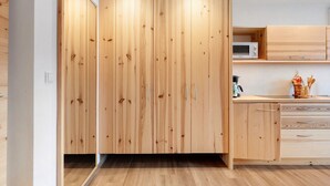 A modern kitchen with wooden cabinets, a microwave, and a countertop with kitchen utensils. - Apartment 'Lärche' with Mountain View, Shared Terrace and Wi-Fi (Bolzano)