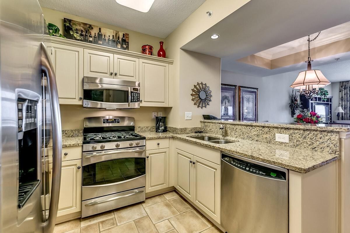 A modern kitchen with stainless steel appliances, granite countertops, and light-colored cabinetry.
