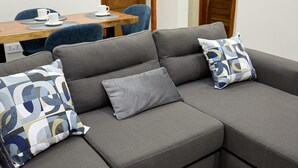 A gray sectional sofa with patterned cushions, a wooden dining table with chairs, and two framed abstract paintings on the wall. -  DSK Residence.  2-bedroom apartment with AC in Accra. (Accra)