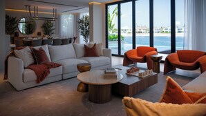 Ein modernes Wohnzimmer mit einer Couch, zwei Sesseln, einem Couchtisch und Blick aufs Meer.