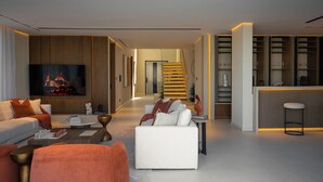 Ein modernes Wohnzimmer mit einer Couch, einem Couchtisch und einem Fernseher. Eine Treppe führt zu einer weiteren Ebene.