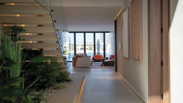 Ein modernes Interieur mit Treppe, Sitzbereich und großen Fenstern mit Blick auf einen Strand.