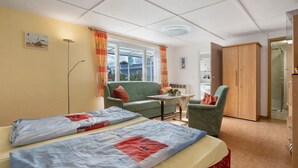 A hotel room with two beds, a sofa, a chair, a small table, and a wardrobe. - Bungalow 'Nati' with Shared Terrace, Garden, and Wi-Fi (Koserow)