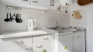 A kitchen with white cabinets, a coffee maker, a sink, and a stove. - Bungalow 'Nati' with Shared Terrace, Garden, and Wi-Fi (Koserow)