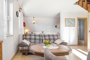 Uma sala de estar acolhedora com uma mesa de centro redonda, um sofá e uma área de jantar com uma mesa de madeira.