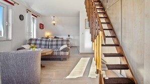 Ein modernes Wohnzimmer mit einer Holztreppe, einem Sofa, einem Couchtisch und einem Teppich.