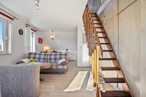 A modern living room with a wooden staircase, a sofa, a coffee table, and a rug.