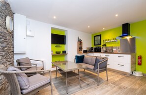 A modern kitchen with a green accent wall, a flat-screen TV, and a built-in oven.