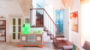 A spacious living area with a staircase, a wooden cabinet, and a door leading to a bathroom. - Le Grind - Terrace with a Great View of the Adriatic Sea and the historic center (Ostuni)