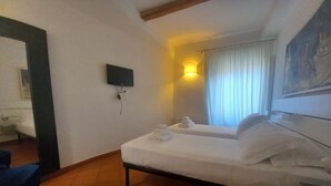 A hotel room with a bed, a TV mounted on the wall, a window with curtains, and a painting on the wall. - Conti Apartment in Firenze (Florence)