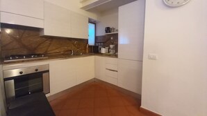 A compact kitchen with white cabinets, a stove, and a microwave. - Conti Apartment in Firenze (Florence)