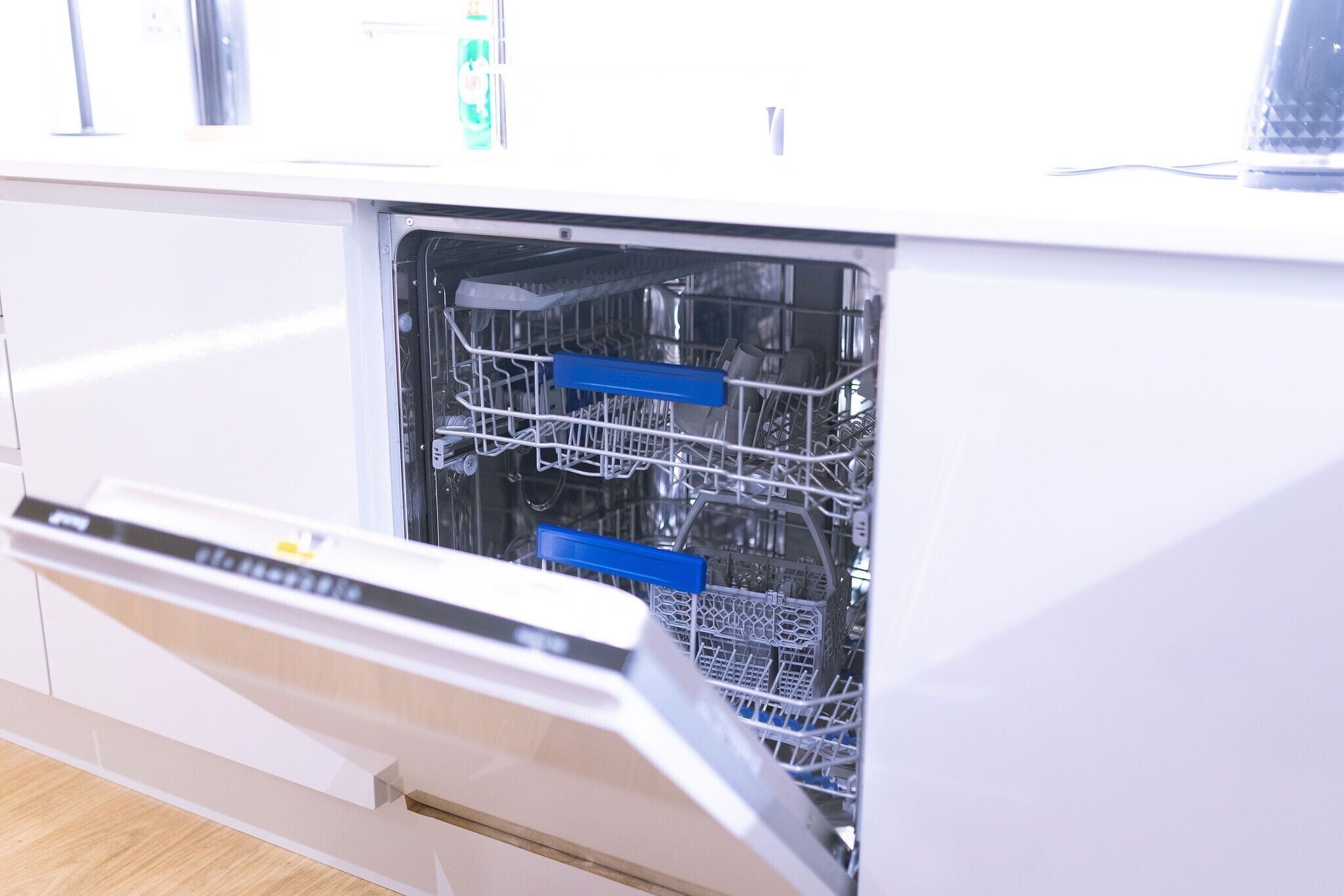 An open dishwasher with racks and utensils inside.