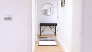 A hallway with a black console table, a round mirror, and a striped rug. - Birmingham City Centre Apartment- Sleeps4-freep (Birmingham)