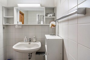A bathroom with a white sink, mirror, and shelves with toiletries. - Apartment 'Haus Rehblick 2, Apt. 4' with Mountain View, Shared Garden and Wi-Fi (Sankt Andreasberg)