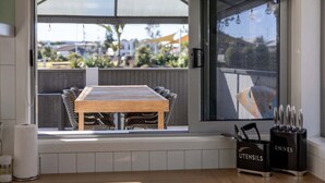 A kitchen with a wooden table and chairs, a window with a view of the outside, and two utensil holders labeled 'UTENSILS' and 'KNIVES'.