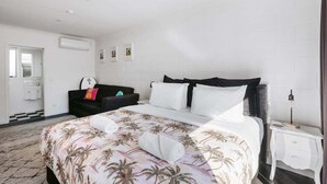 A hotel room with a bed, a black sofa, a nightstand, and a bathroom visible through an open door.