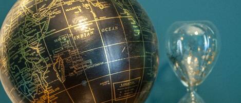 A globe with a stand and an hourglass on a wooden surface.
