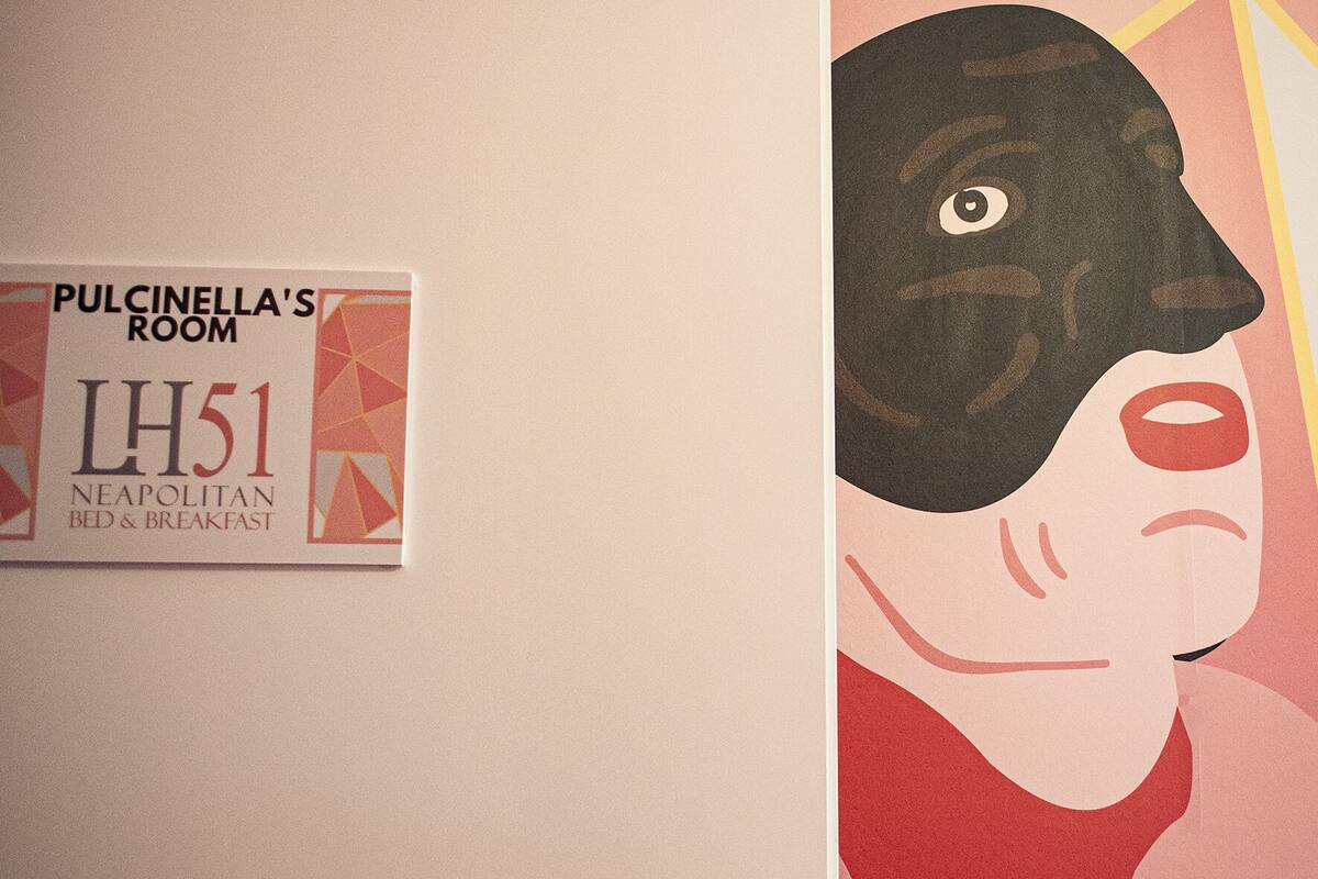 Seinässä on kyltti, jossa lukee: ”Pulcinella’s Room LH51, napolilainen majatalo”.